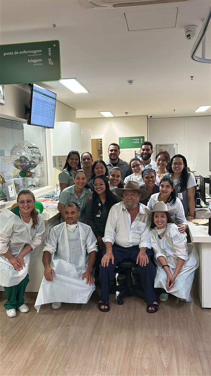 Nelson Barbudo, de chapéu, sentado entre a equipe de enfermagem do hospital ao fim do tratamento